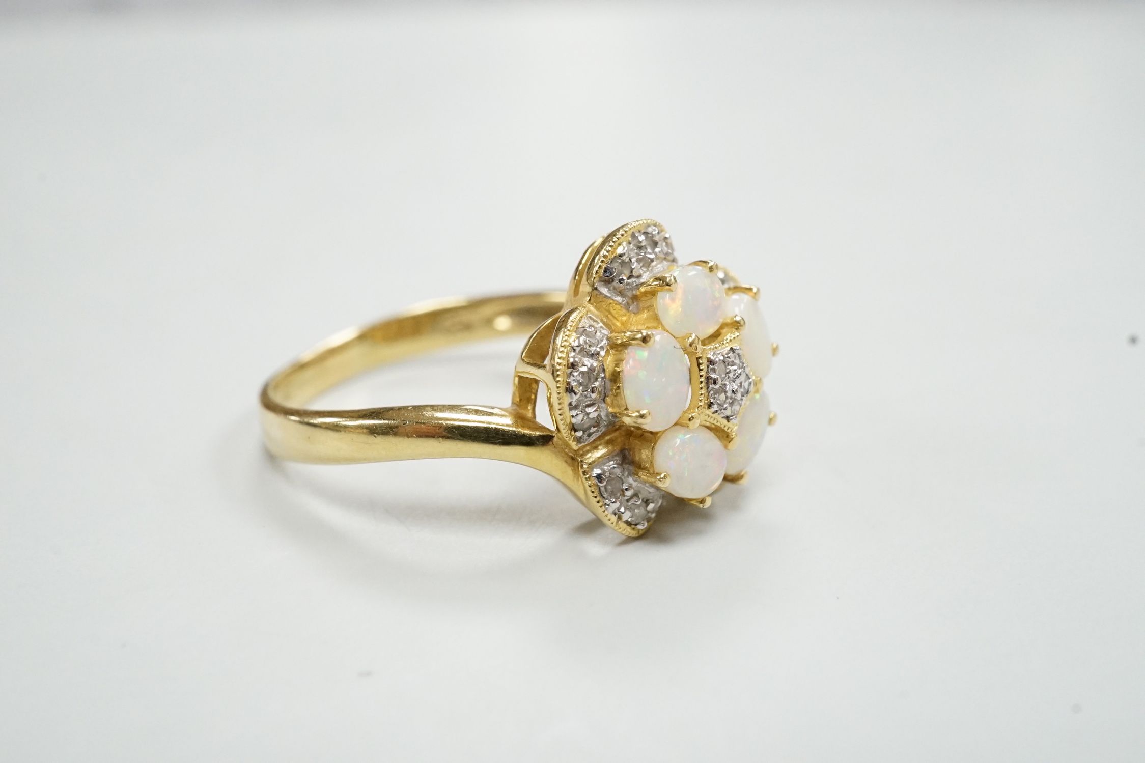 A modern 18k yellow metal, white opal and diamond chip set flower head cluster ring, size P, gross weight 4 grams.